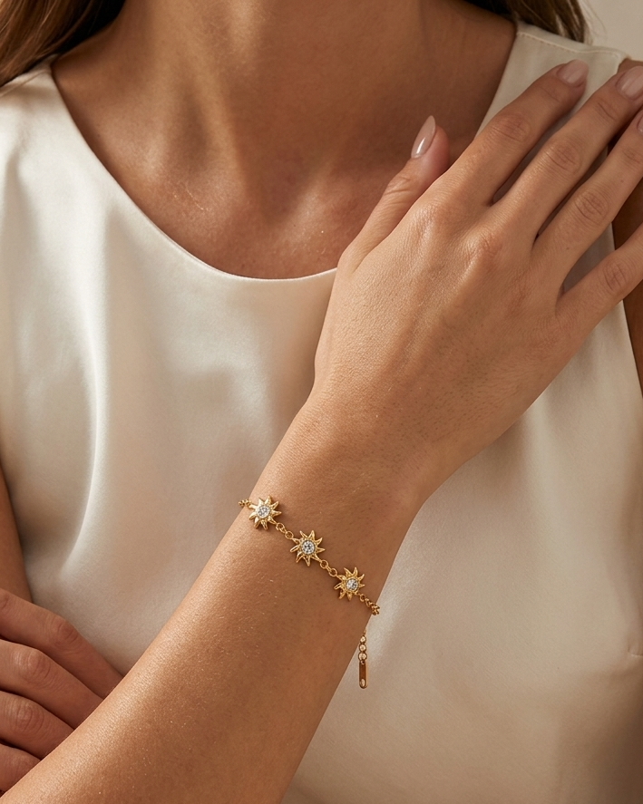 Woman wearing a gold bracelet with star design on a neutral background