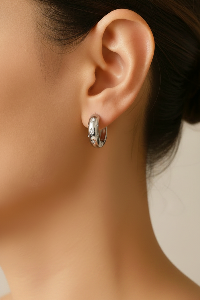 silver hoop earrings worn by a person with a neutral background