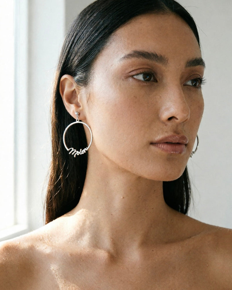Woman wearing hoop earrings with a neutral background