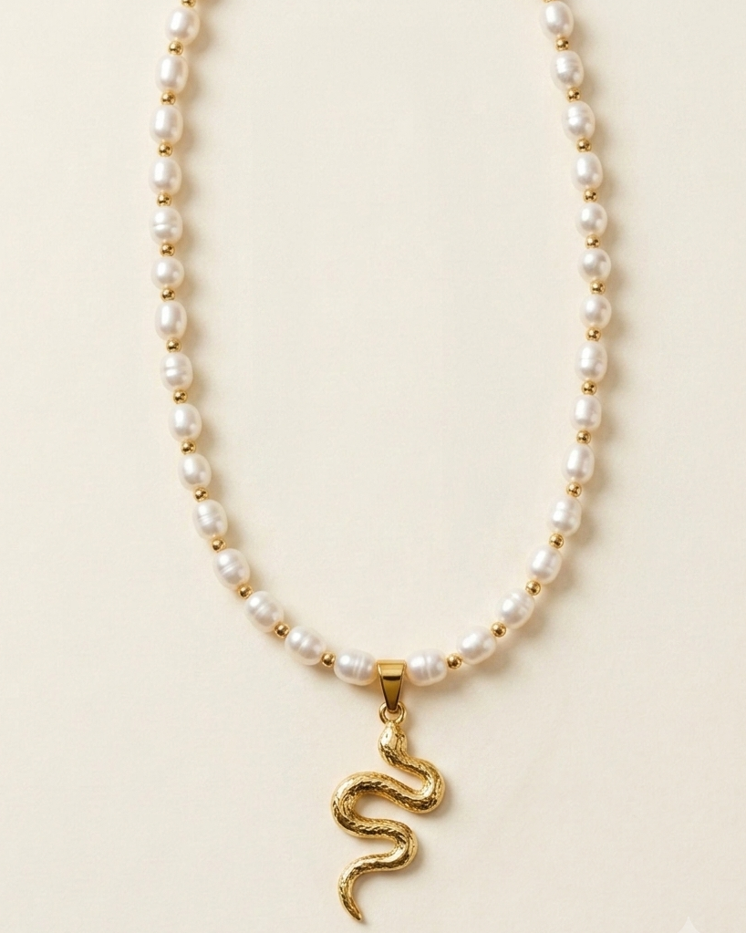 Pearl necklace with a gold snake pendant on a beige background