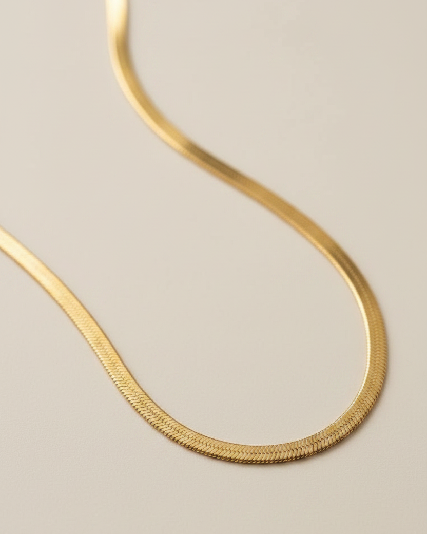 Gold necklace on a textured beige surface