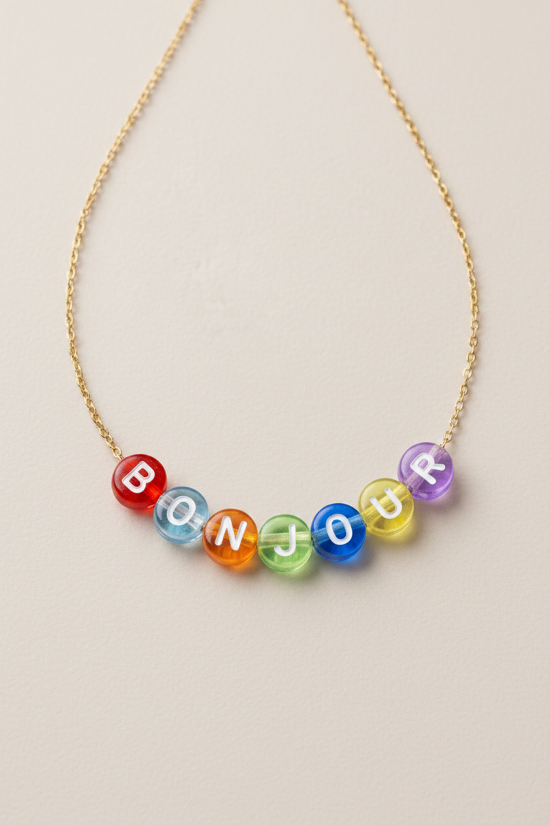 Necklace with colorful beads spelling 'BONJOUR' on a beige background
