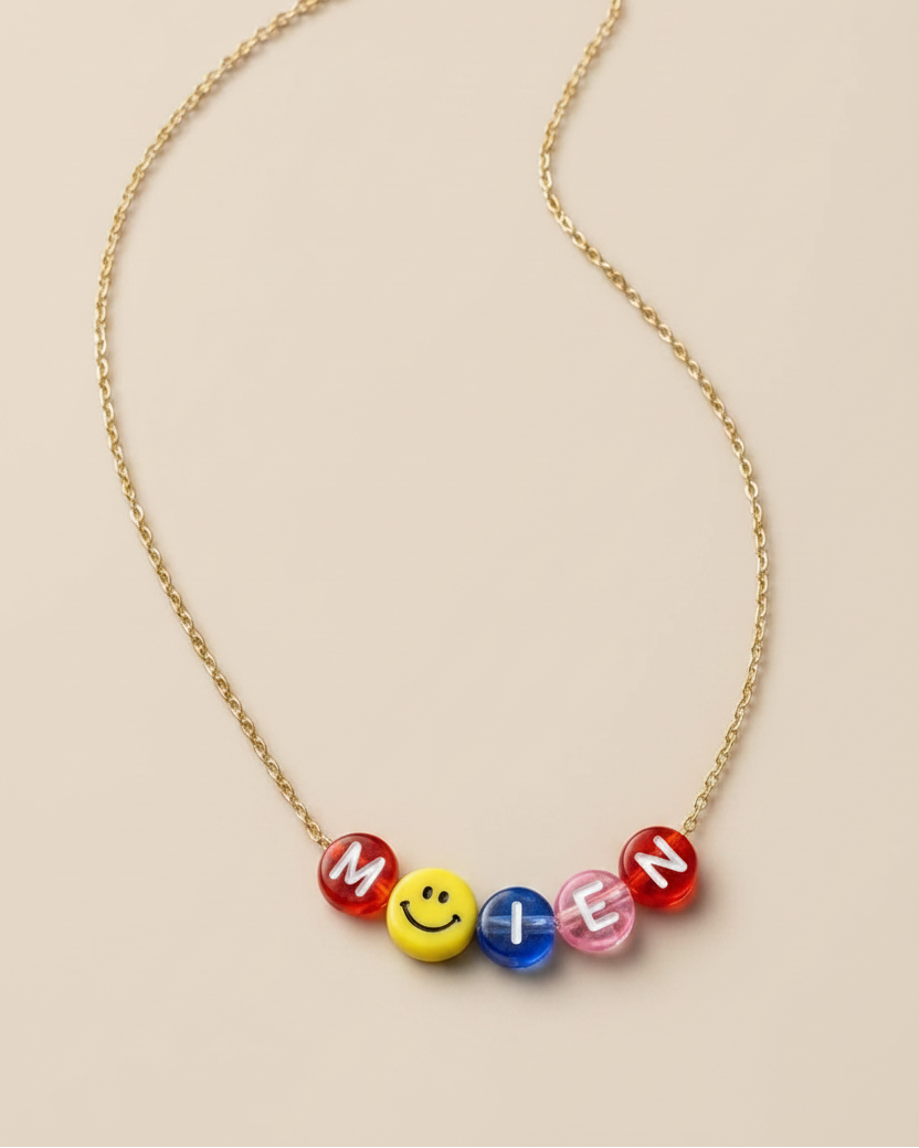 Necklace with colorful beads spelling 'MOIEN' on a beige background